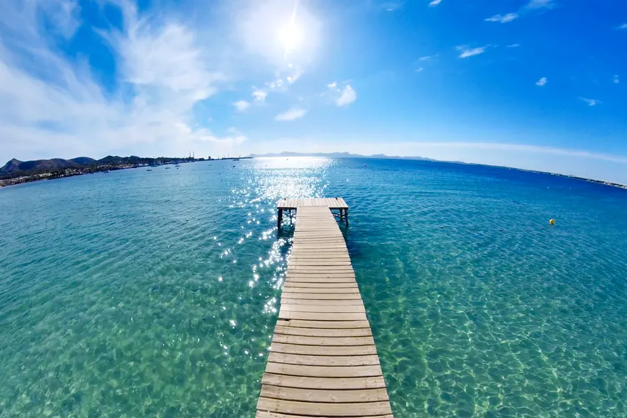 Holzsteg im türkisfarbenen Wasser von Port d’Alcúdia auf Mallorca